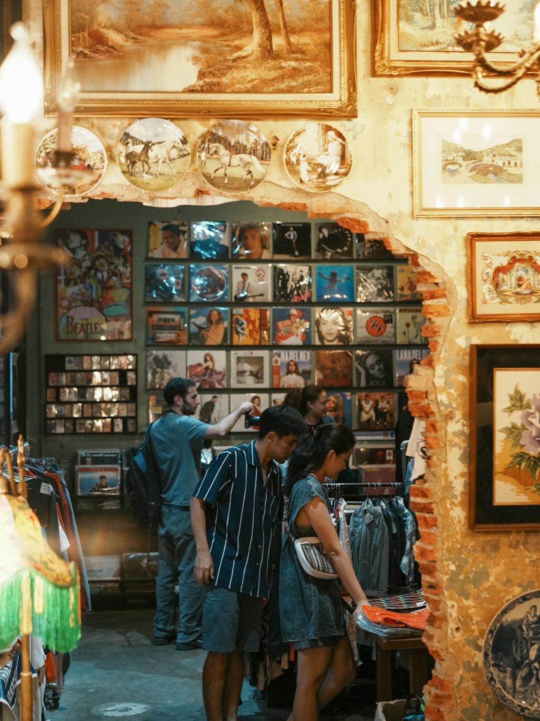 Drei Personen stöbern in Kleiderständern in einem Vintage-Laden.