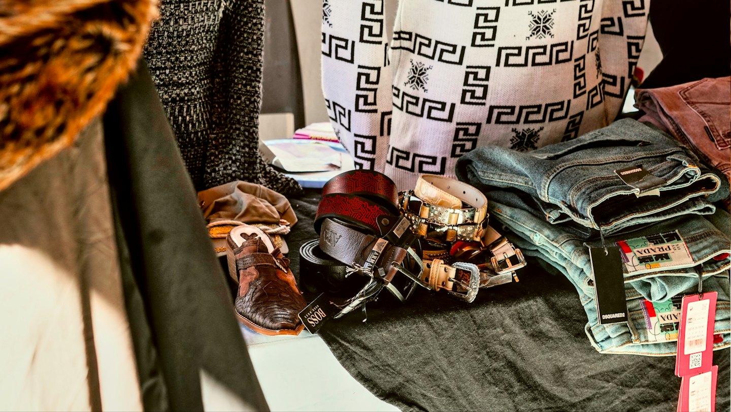 Jeans, Ledergürtel und Kleidung auf dunklem Stoff.
